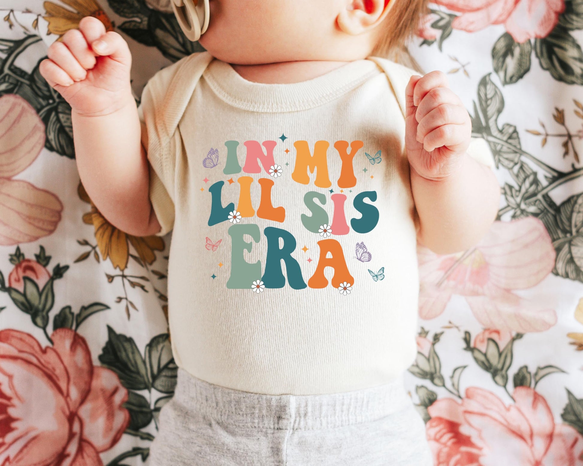 Close-up of butterfly and daisy design on In My Lil Sis Era newborn bodysuit