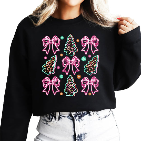 Lifestyle view of women's black Christmas sweatshirt with vibrant neon bow and tree holiday design