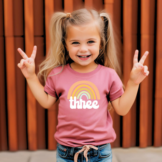 Close-up of retro rainbow birthday graphic on a girls purple 3rd birthday tee by Olive Loves Apple