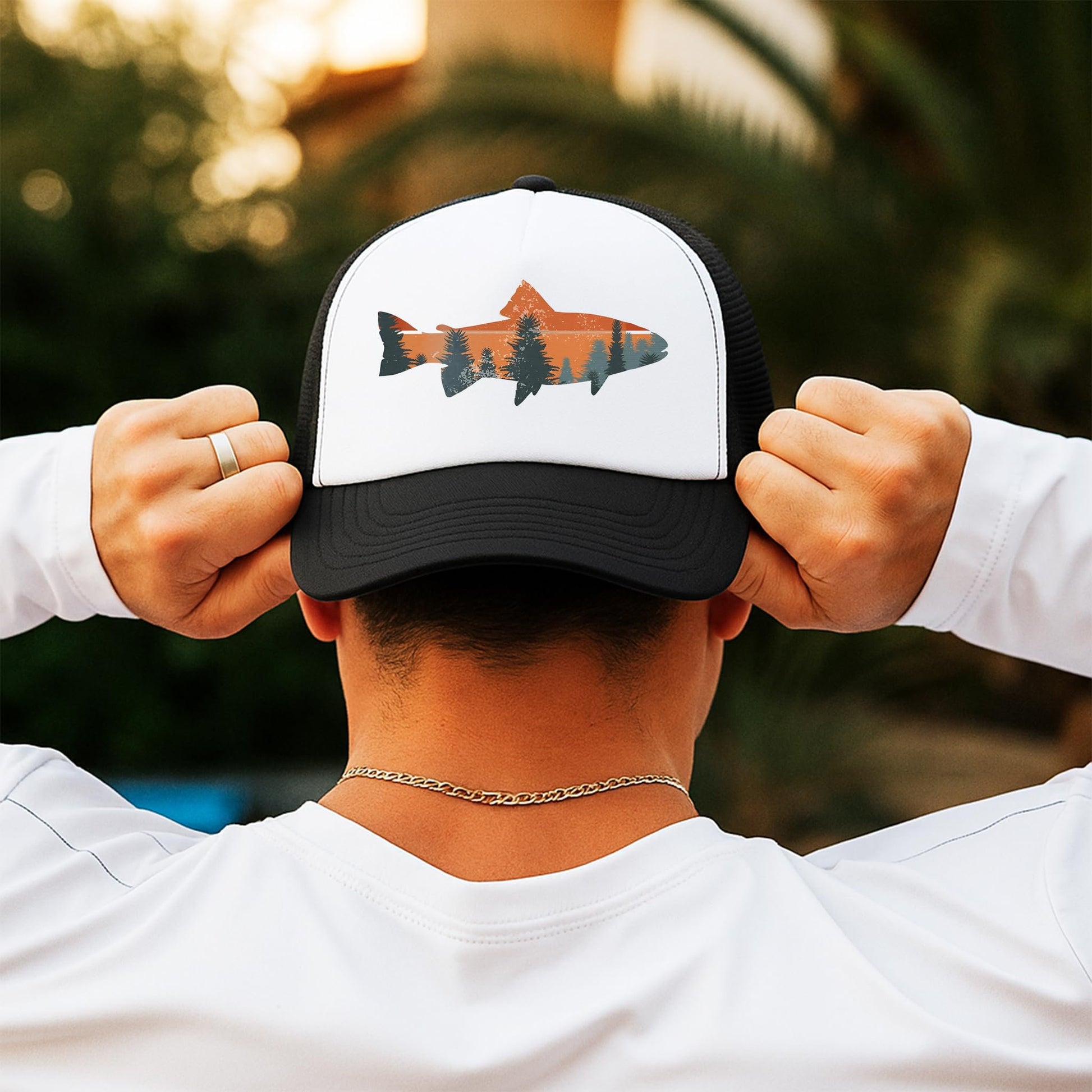 Man wearing trout fishing sunset trucker hat outdoors - white and black snapback back view