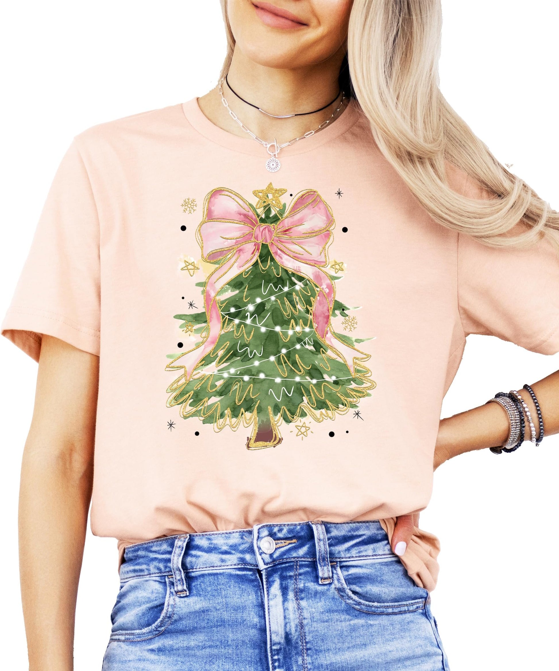 Model wearing festive Christmas tree pink bow tee in peach, casual holiday style