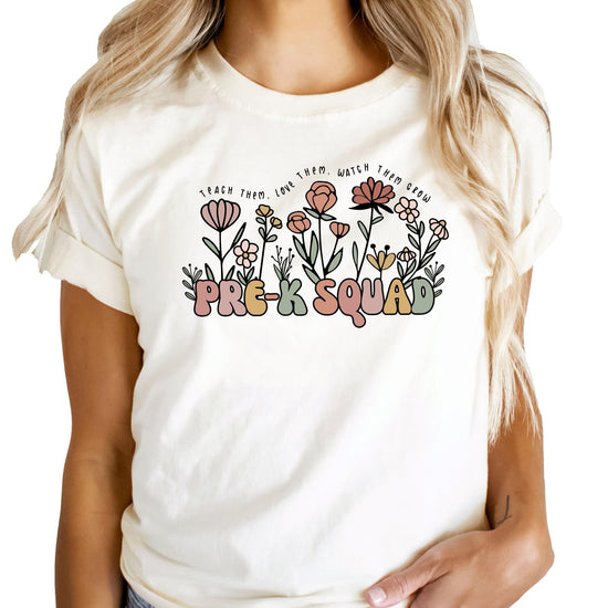 Close-up of retro flower and 'Teach Them Love Them Watch Them Grow' print on peach teacher shirt