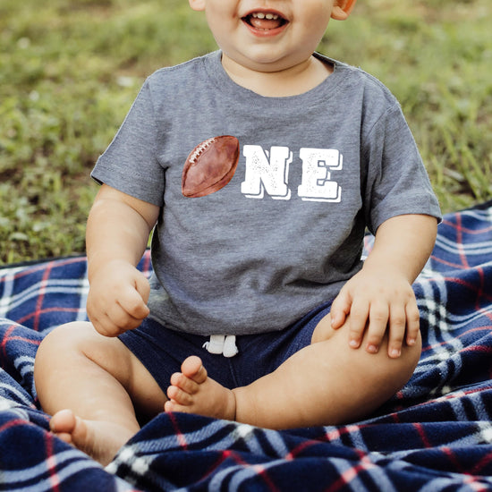Toddler wearing black football first birthday shirt for sports birthday party