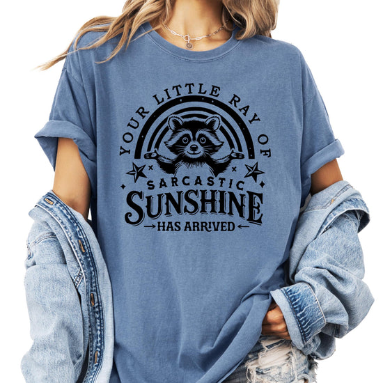 Flat lay of ivory t-shirt showing full raccoon graphic and text design