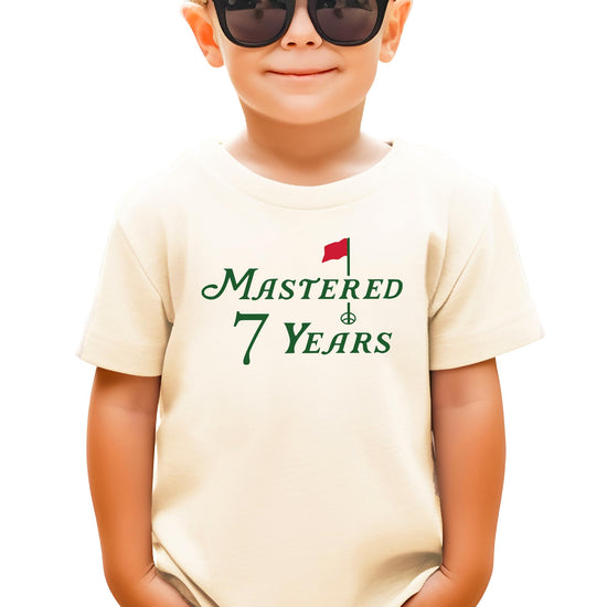 Natural kids tee with Mastered 7 Years golf-themed birthday graphic for boys and girls