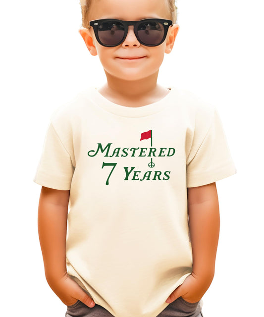 Natural kids tee with Mastered 7 Years golf-themed birthday graphic for boys and girls