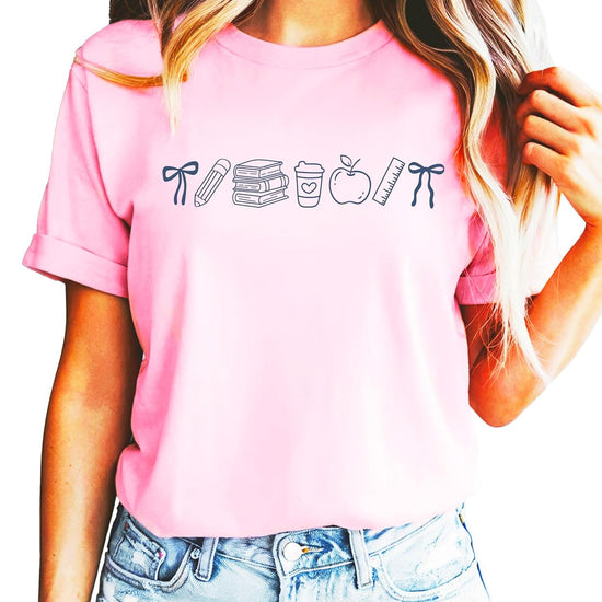 Flat lay of pink back to school graphic tee with bow and school supplies design on light background