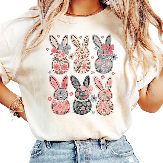 Women's ivory graphic tee with six retro floral bunnies and coquette bows, laid flat on a light background