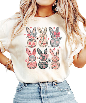 Women's ivory graphic tee with six retro floral bunnies and coquette bows, laid flat on a light background