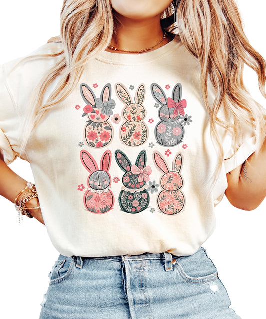 Women's ivory graphic tee with six retro floral bunnies and coquette bows, laid flat on a light background