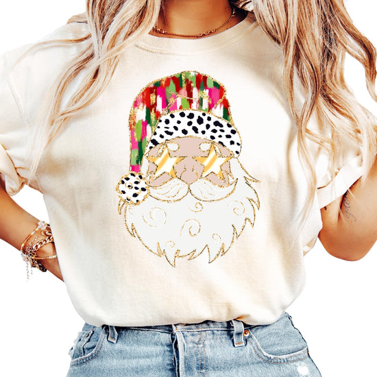 Close-up of vibrant Santa with gold sunglasses print on soft ivory holiday graphic tee for women